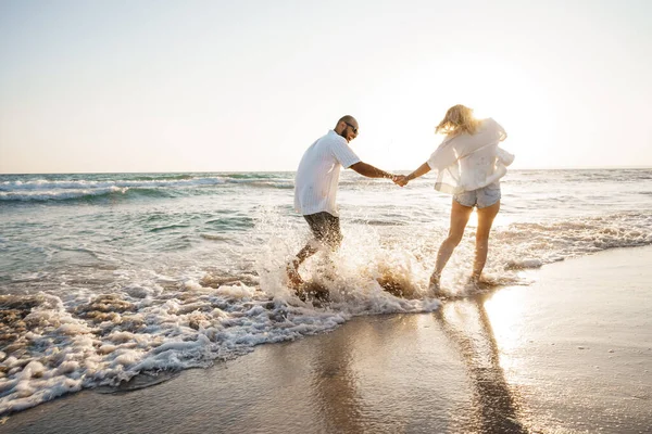 Young beautiful couple walking on beach near sea — Stock Photo, Image
