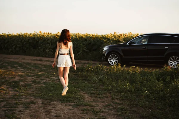 Junge Frau stoppte ihr Auto in Sonnenblumenfeld — Stockfoto