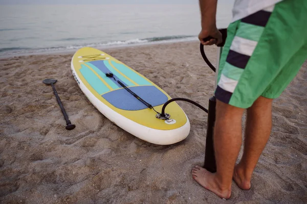 Close up of man prepares to paddle surf on a beach inflating sup board — Stock Photo, Image