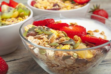 Ahşap masa üstü görünümünde yoğurt, çilek ve granola ile sağlıklı kahvaltı
