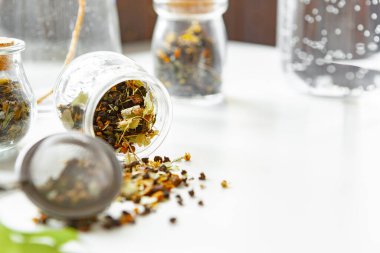 Kuru çay yapraklı cam kavanozlar beyaz masaya yakın.