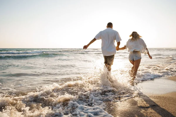 Young beautiful couple walking on beach near sea — Stock Photo, Image