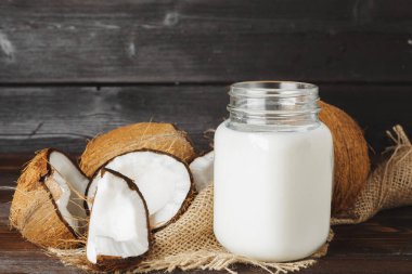 Siyah ahşap arka plan üzerinde kırık hindistan cevizi ve hindistan cevizi sütü