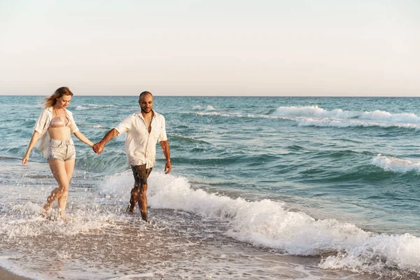 Jovem casal bonito andando na praia perto do mar — Fotografia de Stock