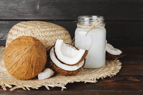 Lait de coco cassé et lait de coco sur fond de bois noir — Photo