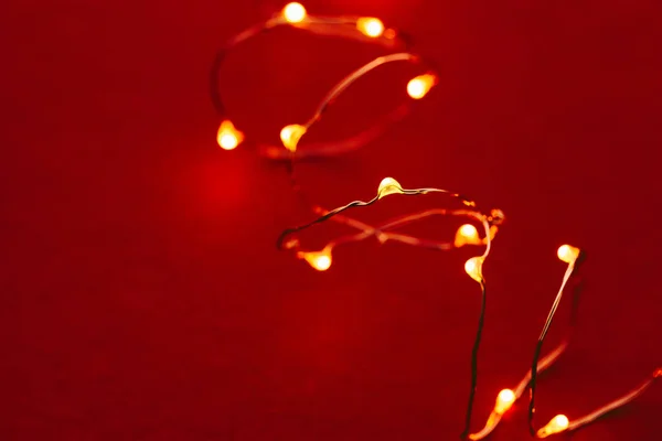 Czerwone tło z oświetlonymi światłami girlandy — Zdjęcie stockowe