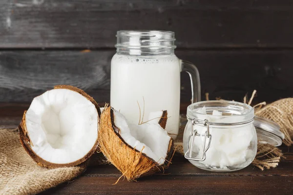 Coco quebrado e leite de coco em fundo de madeira preta — Fotografia de Stock