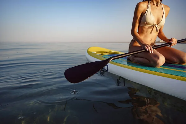 Close up of young woman sitting on a stand up paddle board — Stock Photo, Image