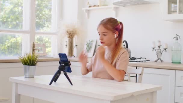 Дівчина-підліток має відеодзвінок через смартфон вдома на кухні — стокове відео