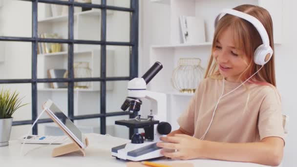 Девочка-подросток, использующая микроскоп для исследований во время онлайн-обучения на дому — стоковое видео