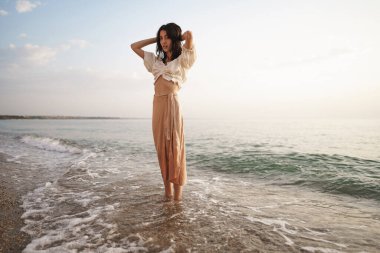 Yalnız genç kadın gün batımında sahilde yürüyor.