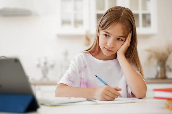 Ragazza adolescente che prende appunti nel blocco note, facendo i compiti a tavola a casa — Foto Stock