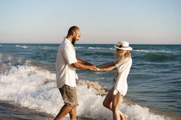 Junges schönes Paar zu Fuß am Strand in der Nähe des Meeres — Stockfoto