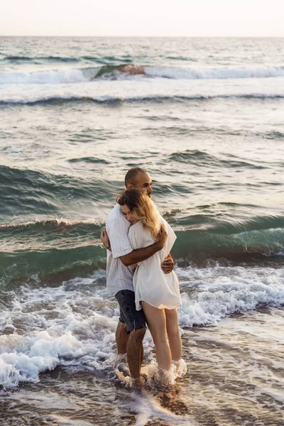 Красивая молодая пара обнимается на пляже у воды — стоковое фото