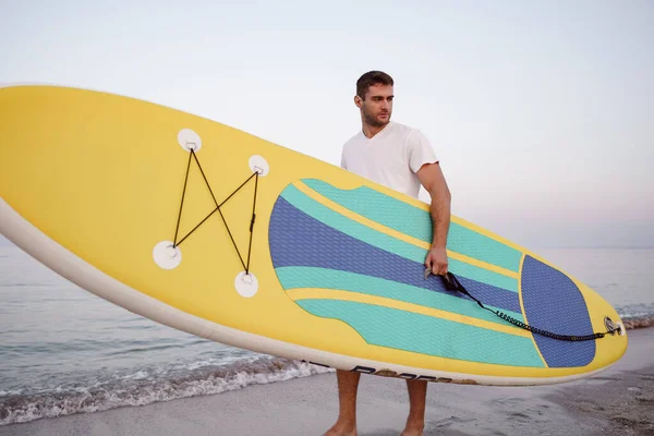 Young man carrying sup board after water surf session — Stock Photo, Image