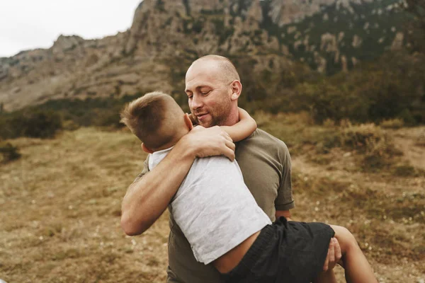 Отец и его маленький сын обнимаются на прогулке в горах — стоковое фото