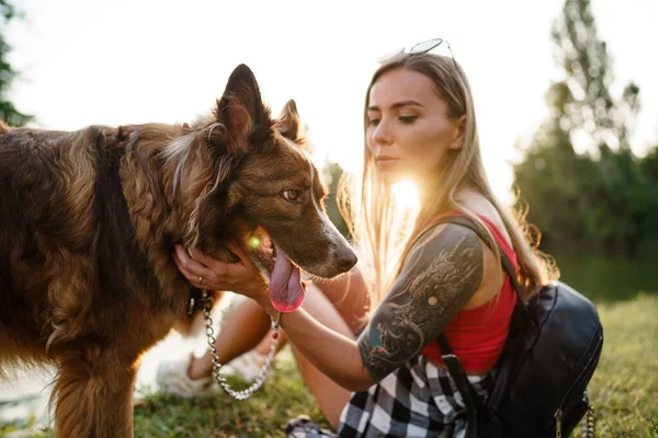 Jovem bela mulher acariciando seu cão bonito no parque — Fotografia de Stock