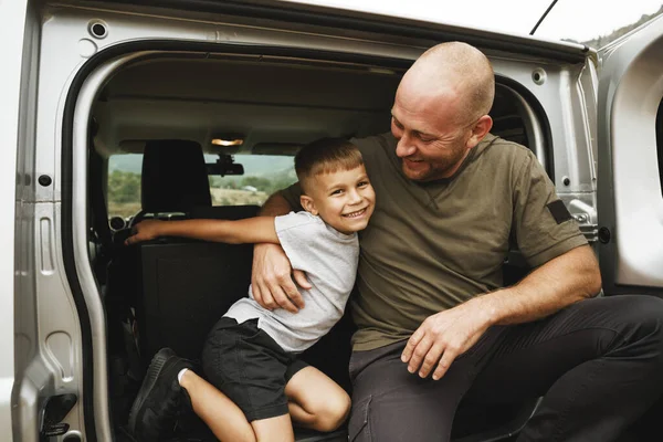 Счастливые отец и сын сидят в багажнике машины — стоковое фото