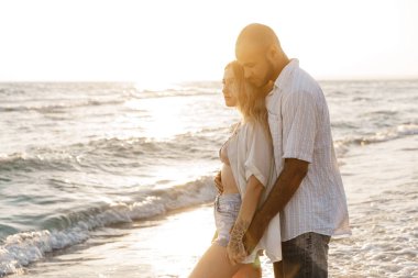 Deniz kıyısındaki genç mutlu çift denizin tadını çıkarıyor.