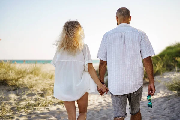 Jeune couple heureux tenant la main et marchant ensemble vers la plage le jour de l'été — Photo