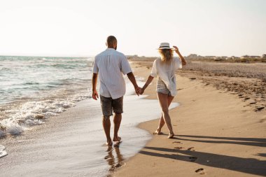 Young beautiful couple walking on beach near sea clipart