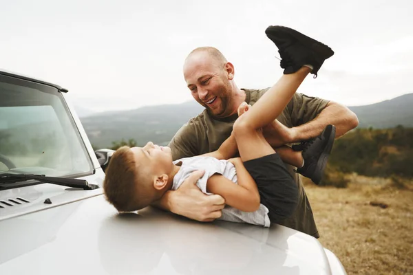 Папа и сын играют на капоте машины в дороге — стоковое фото