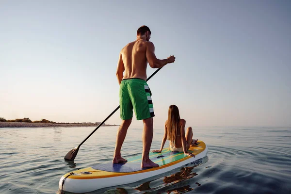 Paar toeristen jonge man en vrouw hebben plezier peddelen op zee — Stockfoto