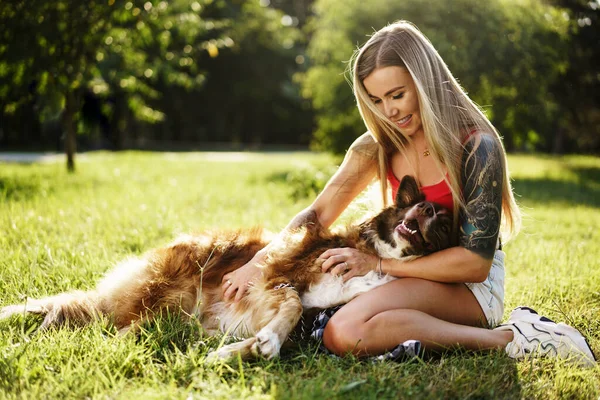 Mladá krásná žena mazlení její roztomilý pes v parku — Stock fotografie
