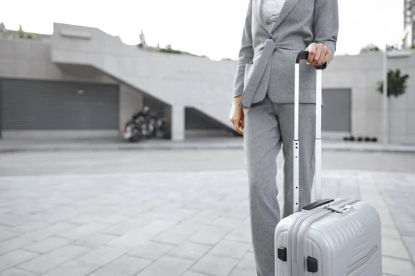 Mujer de negocios en traje gris en viaje de negocios caminando con su equipaje en la ciudad —  Fotos de Stock