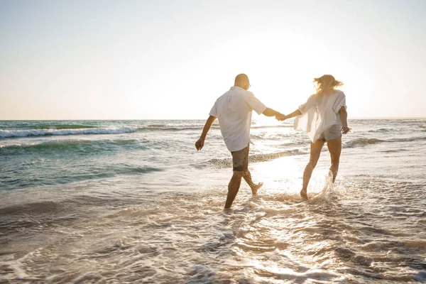 Young beautiful couple walking on beach near sea — Stock Photo, Image