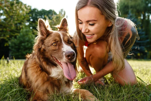 Detail mladé feny se svým psem sedí na trávě v parku — Stock fotografie