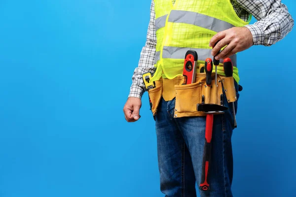 Studio shot of unknown handyman with hands on waist and tool belt with construction tools — Stock Photo, Image