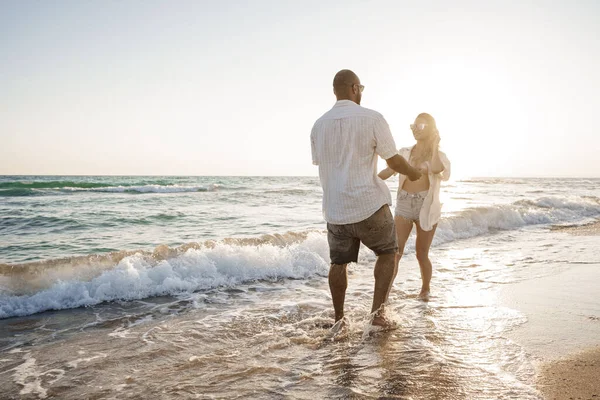 Young beautiful couple walking on beach near sea — Stock Photo, Image