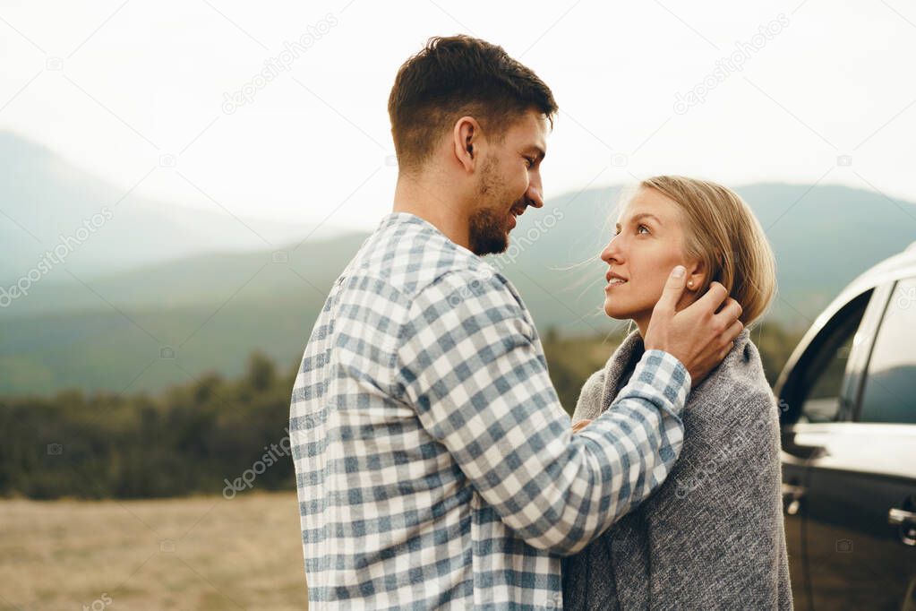 Happy loving couple hiking and hugging in mountains