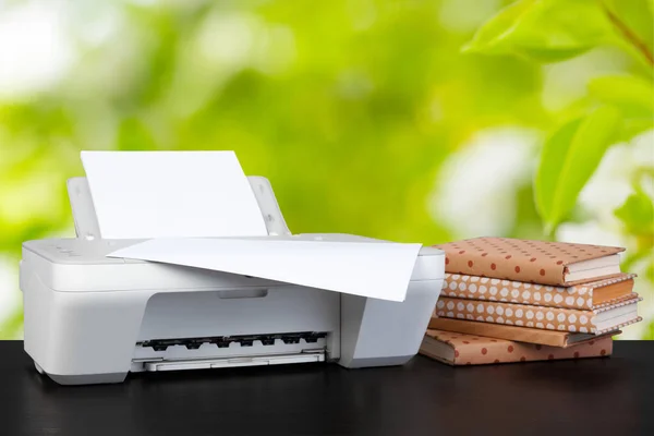 Impresora doméstica compacta en el escritorio con libros sobre fondo borroso — Foto de Stock