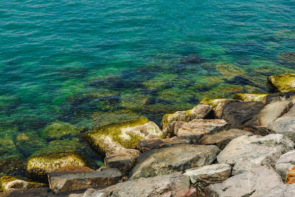 Close up of stones and clear water on the shore of a beach