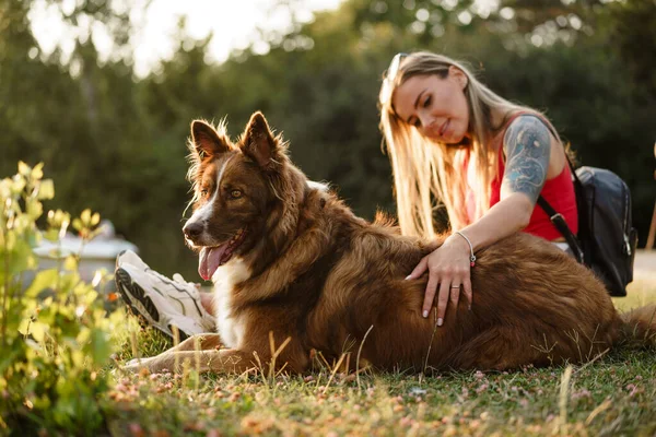 Joven hermosa mujer acariciando su lindo perro en el parque — Foto de Stock