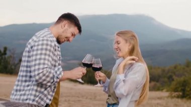 Genç çift dağlara karşı şarap içip flört ediyor.