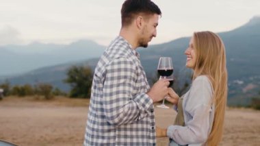 Genç çift dağlara karşı şarap içip flört ediyor.