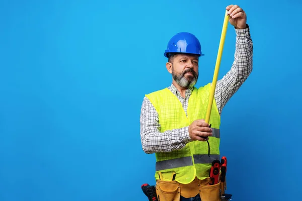 Férfi építő gazdaság mérési rulett a kék háttér — Stock Fotó