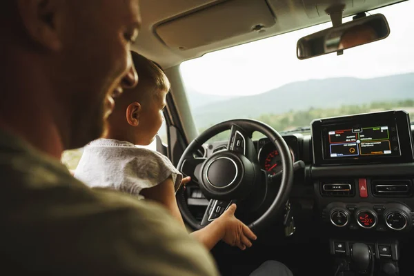 Père enseigne petit fils à conduire sur la route — Photo