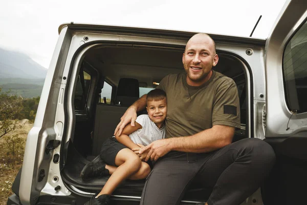 Счастливые отец и сын сидят в багажнике машины — стоковое фото