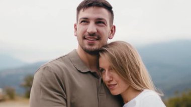 Genç ve sevgi dolu bir çift dağlarda durup sarılıyor. 