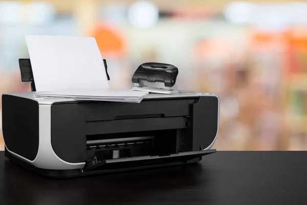 Kompakter Laserdrucker auf schwarzem Schreibtisch vor verschwommenem Hintergrund — Stockfoto