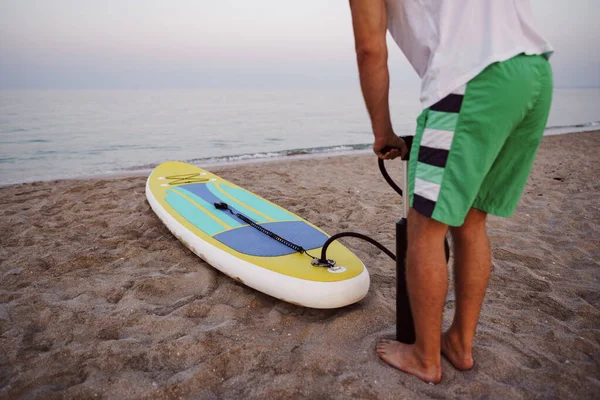 Close up of man prepares to paddle surf on a beach inflating sup board — Stock Photo, Image