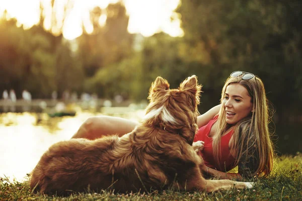 Närbild av ung kvinna med sin hund sitter på gräs i parken — Stockfoto