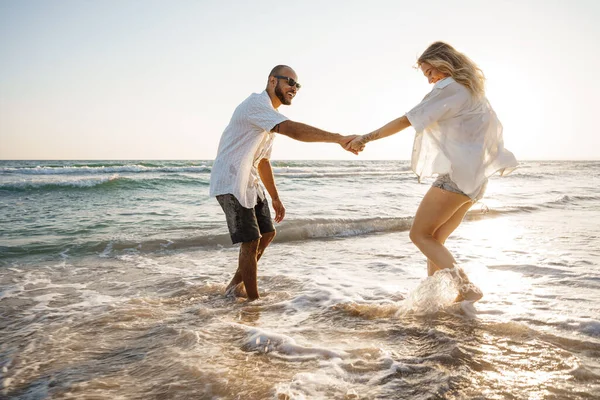 Young beautiful couple walking on beach near sea — Stock Photo, Image