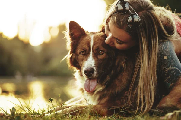 Close up portrait of young woman kissing her dog in the park — Stock Photo, Image