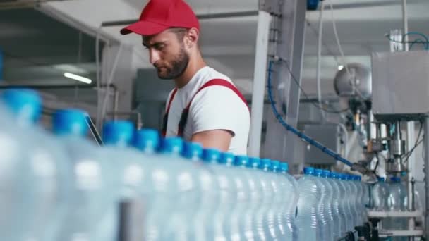 Ung arbetare i vattenfabriken kontrollerar kvaliteten och gör inspektion i linjeproduktion — Stockvideo