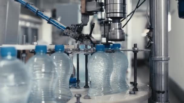 Waterfabriek industriële machine zet doppen op plastic petflessen met water, close-up — Stockvideo